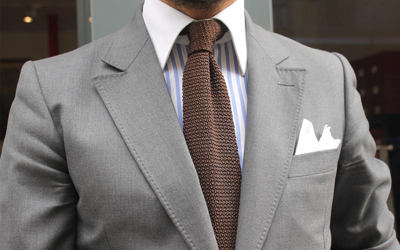 Hnedá kravata v sivom obleku